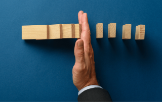 Hand stoppt das fallen von Dominosteinen